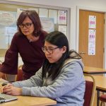 a woman showing a woman something on the laptop